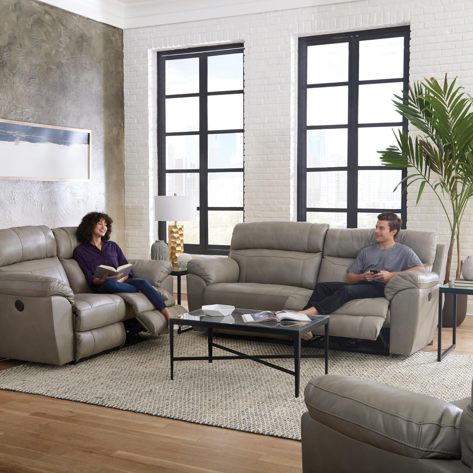 Living room with gray reclining sofas, a coffee table, and two people sitting.