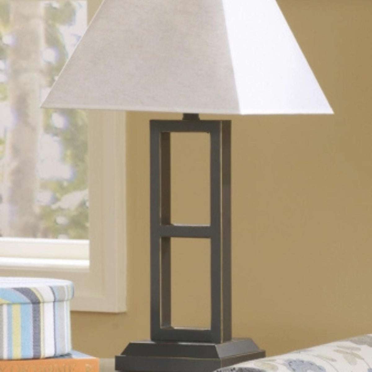 Table lamp with a white shade on a wooden base in a room setting.