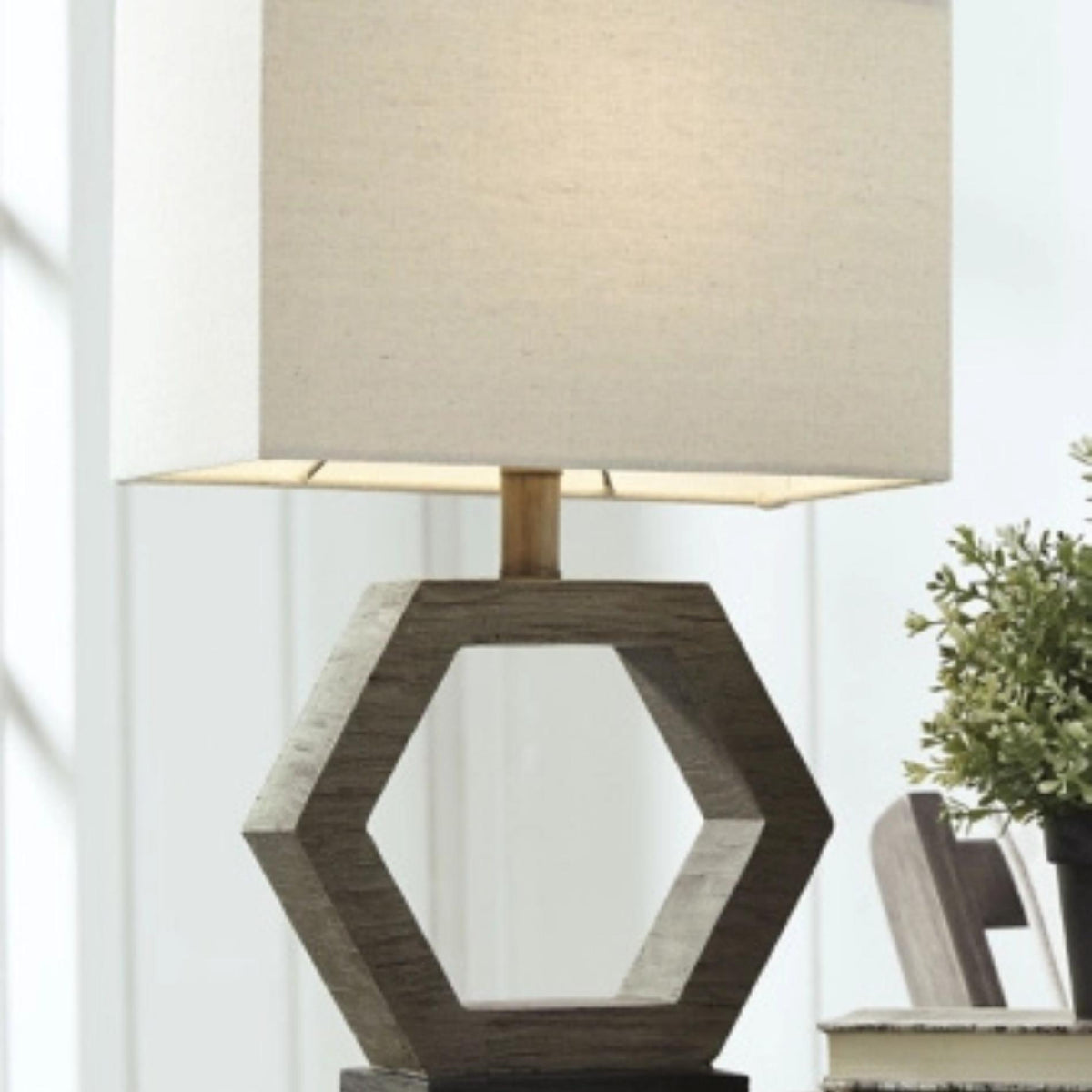 Table lamp with hexagonal wooden base and beige lampshade on a white background