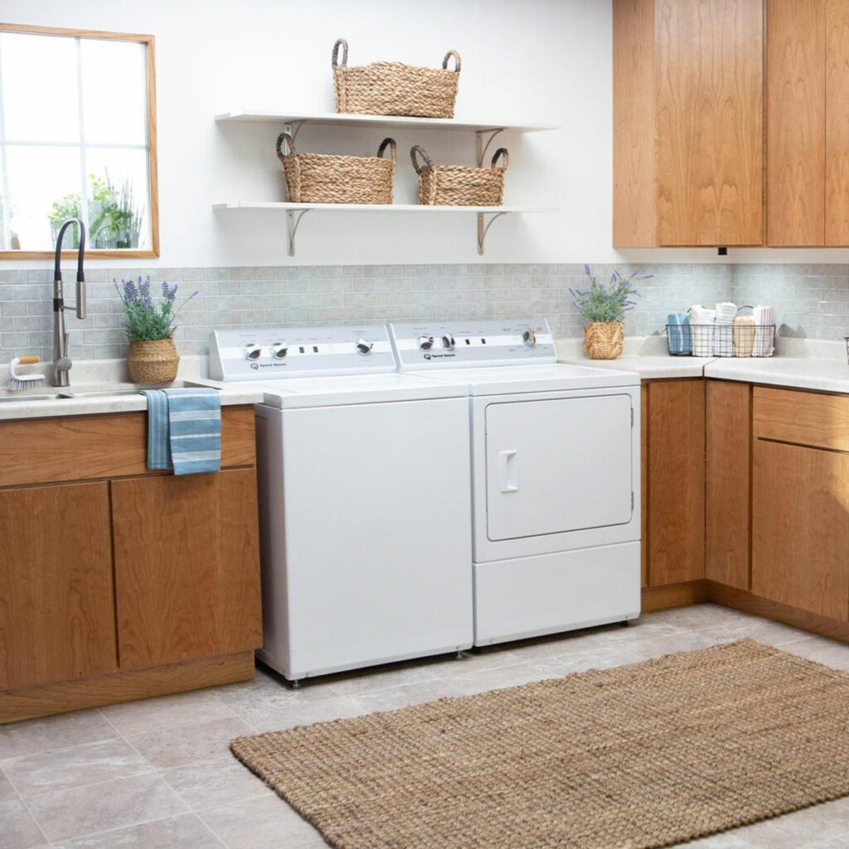 White washer and dryer in a kitchen with wooden cabinets and a rug on the floor.