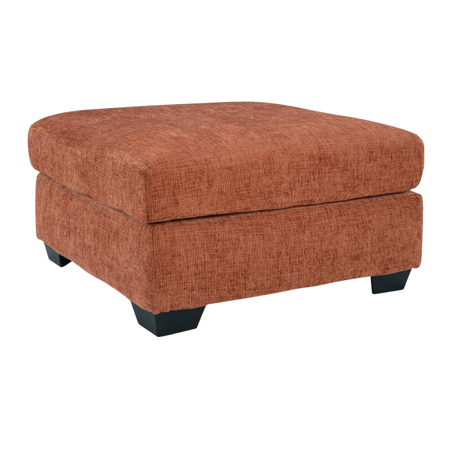 A square upholstered ottoman in a textured rust-orange fabric, featuring black block feet, shown against a plain white background.