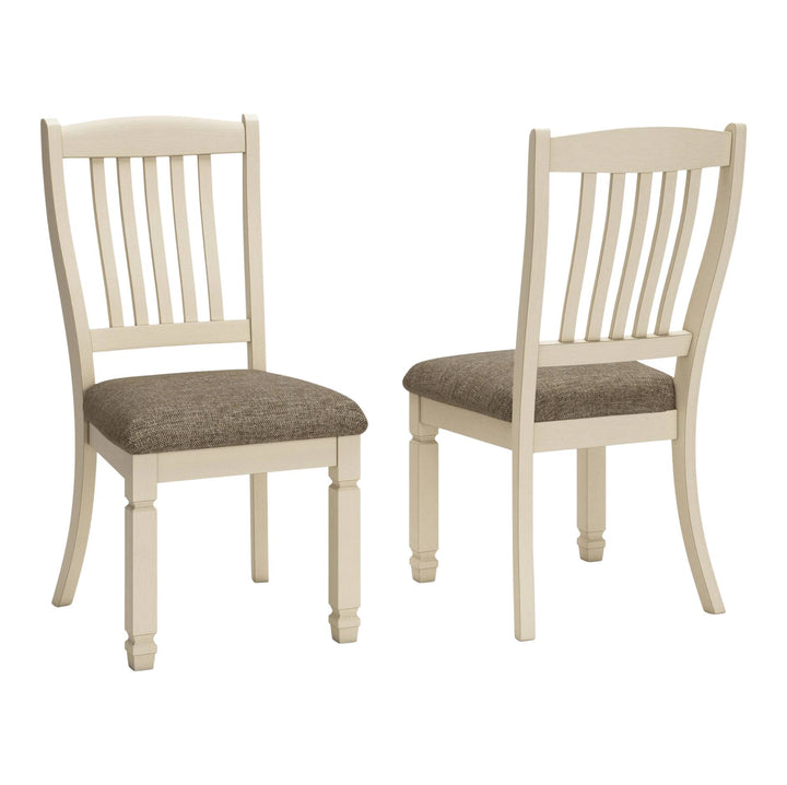 Two cream-colored wooden dining chairs with slatted backs and brown upholstered seats, shown on a plain white background.