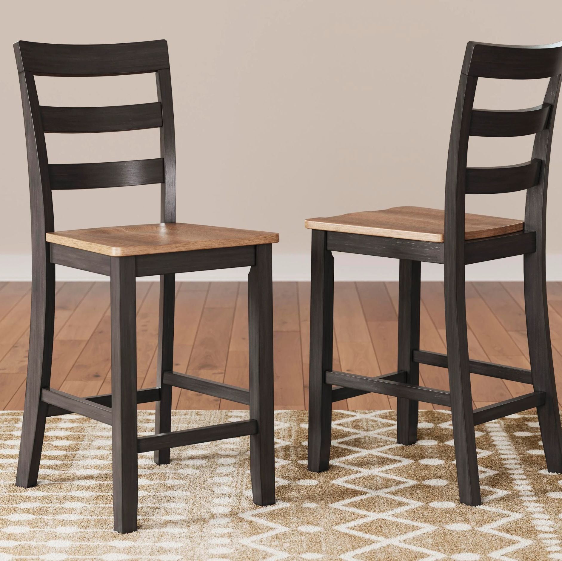 Two counter-height bar stools with dark brown frames and light brown wooden seats, shown in a room setting with a patterned rug and wood floor.