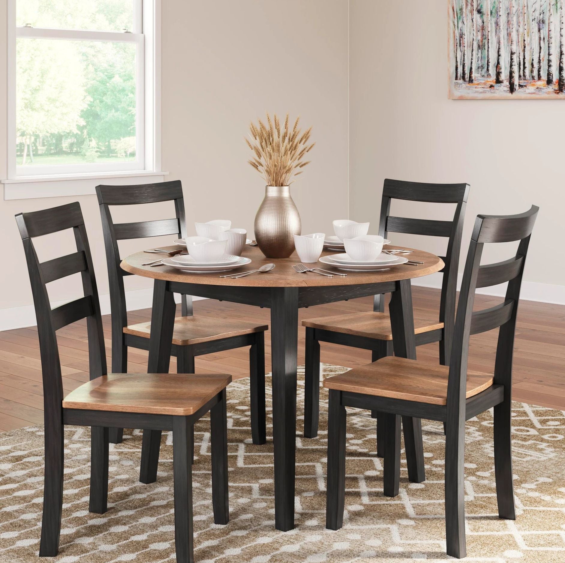 A 5-piece round dining table set with four black ladder-back chairs featuring light brown wooden seats, shown in a bright dining room setting with a window, patterned rug, and tableware.