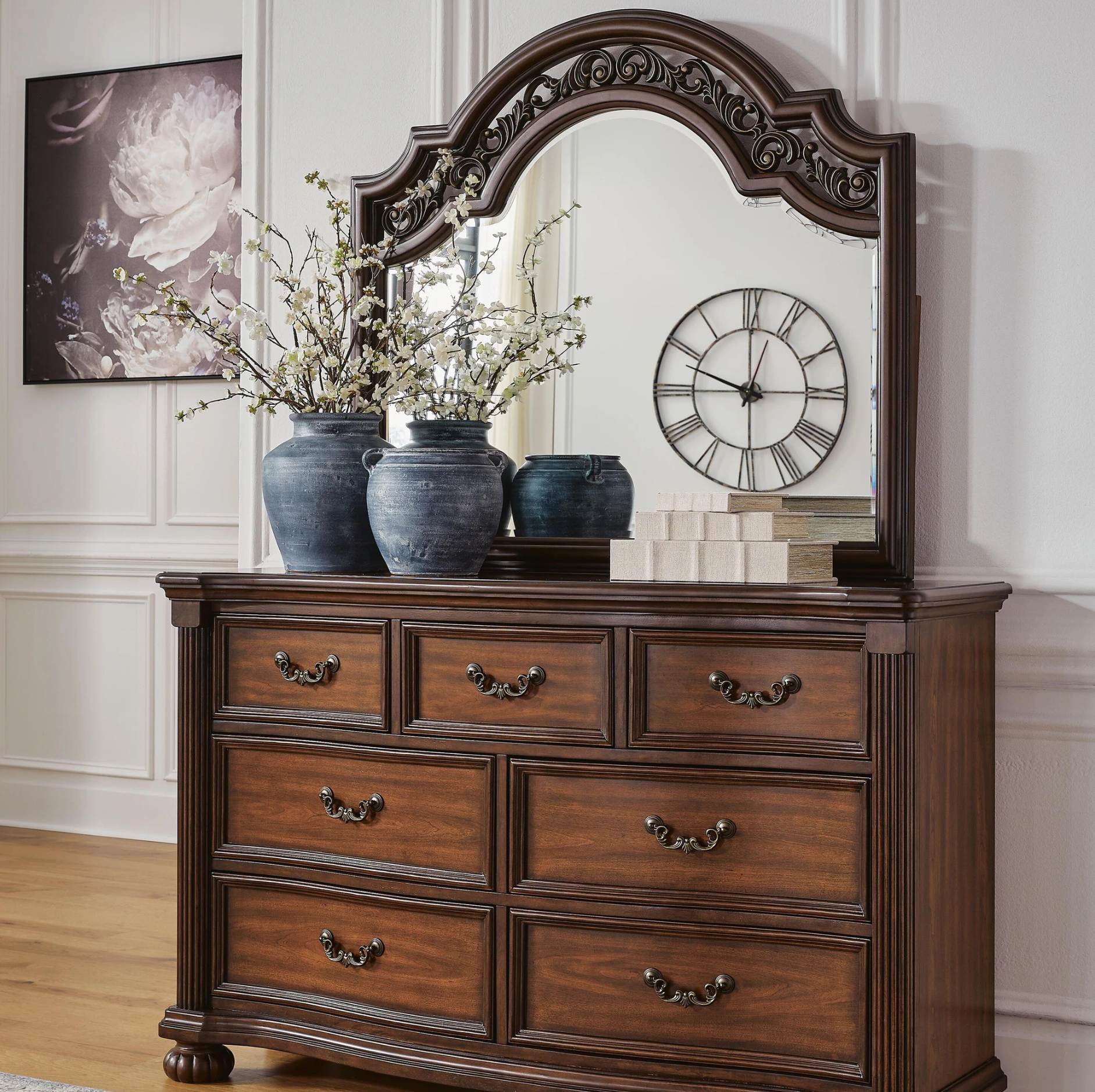 Wooden dresser with mirror, decorative vases, and clock in a room setting.