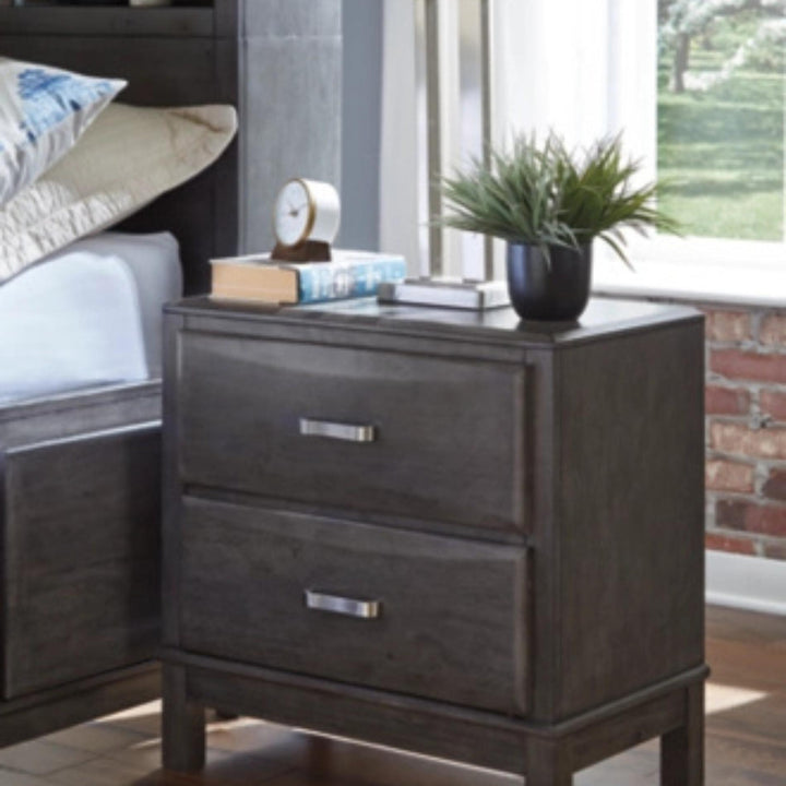 Wooden nightstand with two drawers, books, and a plant in a bedroom setting.