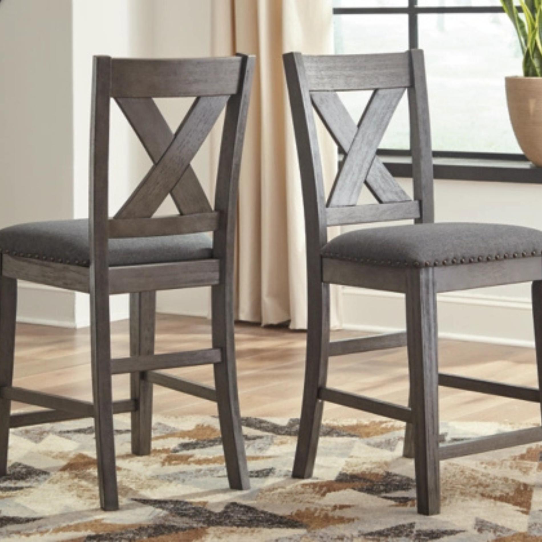 Two gray wooden bar stools with X-shaped backrests on a patterned rug.
