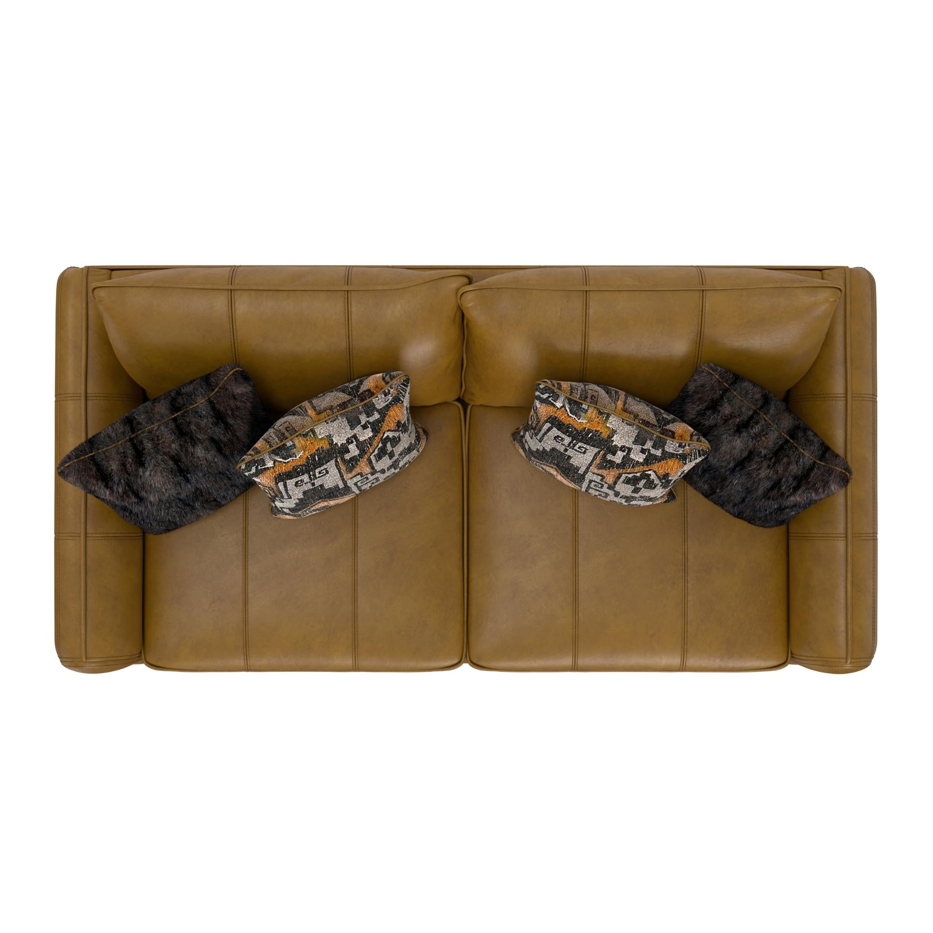 Brown leather sofa with camouflage-patterned pillows on a white background