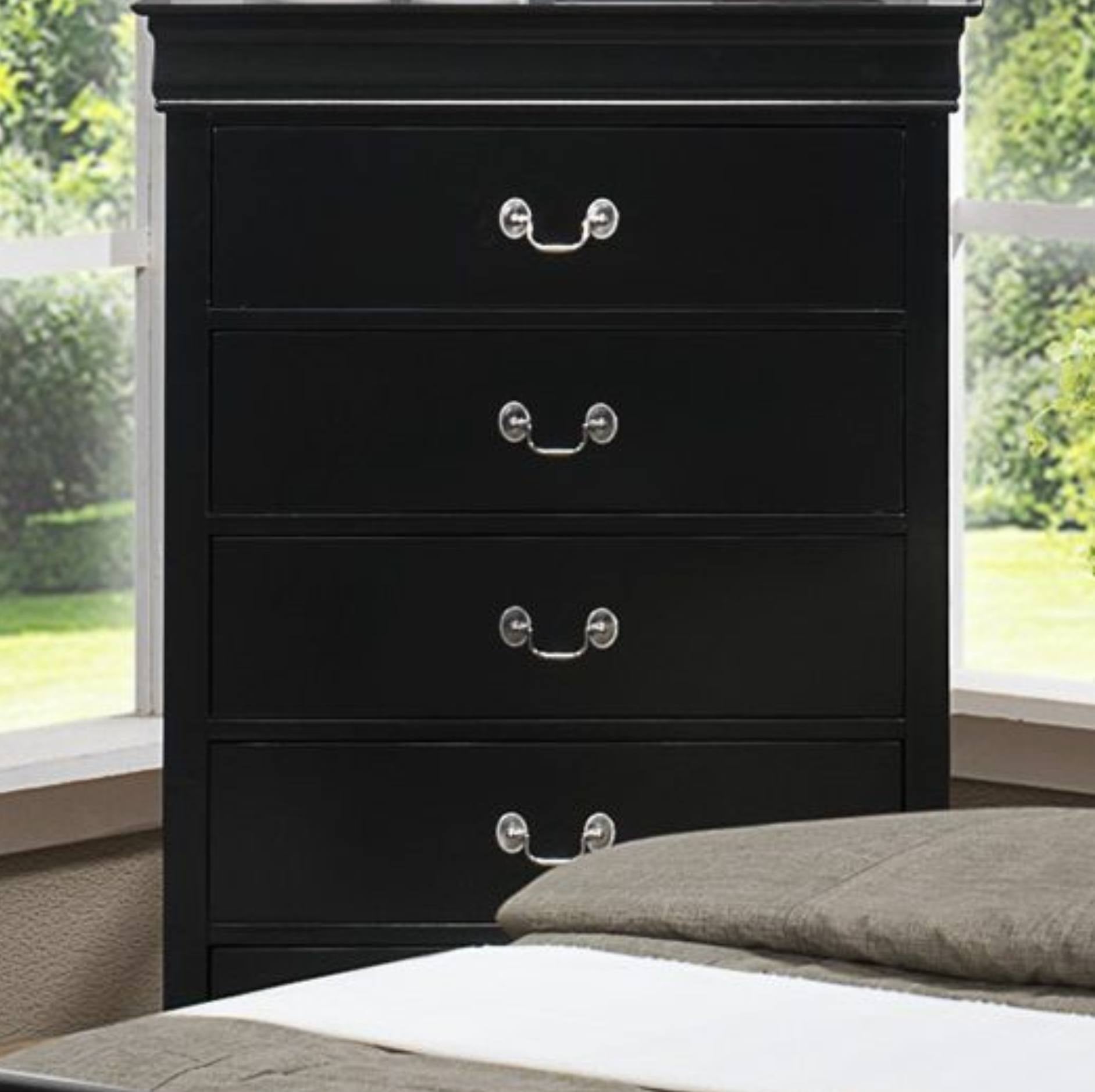 A black wooden four-drawer dresser with silver metal handles, positioned next to a bed in a bedroom setting with windows and greenery visible outside.