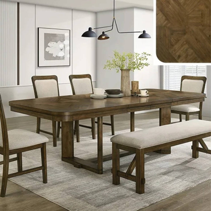 A rectangular wooden dining table set in a bright dining room, surrounded by four upholstered chairs and a matching bench. The table has a medium brown wood finish, and the chairs and bench have light beige cushions.