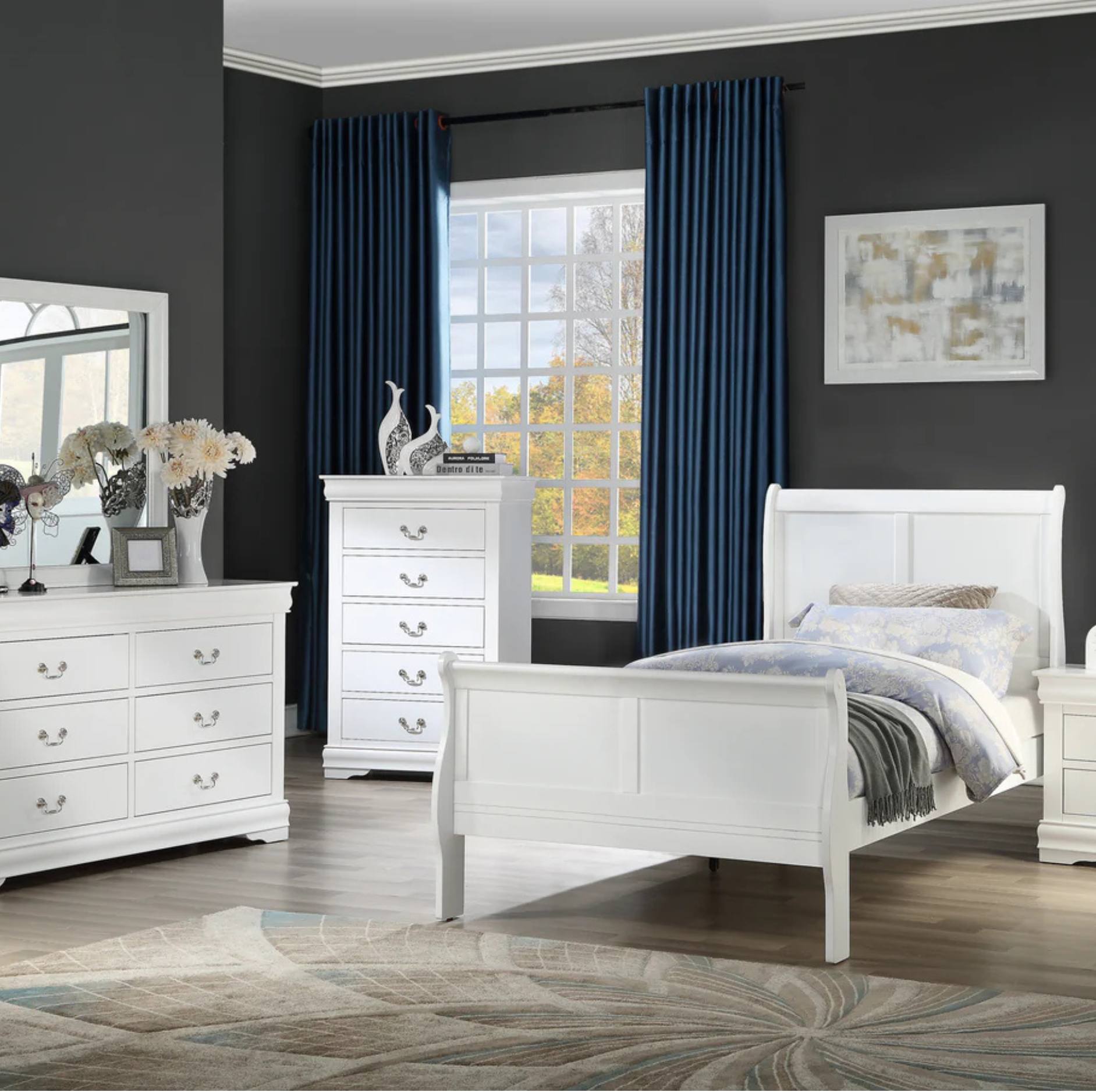 A staged bedroom featuring a white wooden bed frame, matching white dresser, and white chest of drawers, set against dark gray walls with deep blue curtains and a window view.
