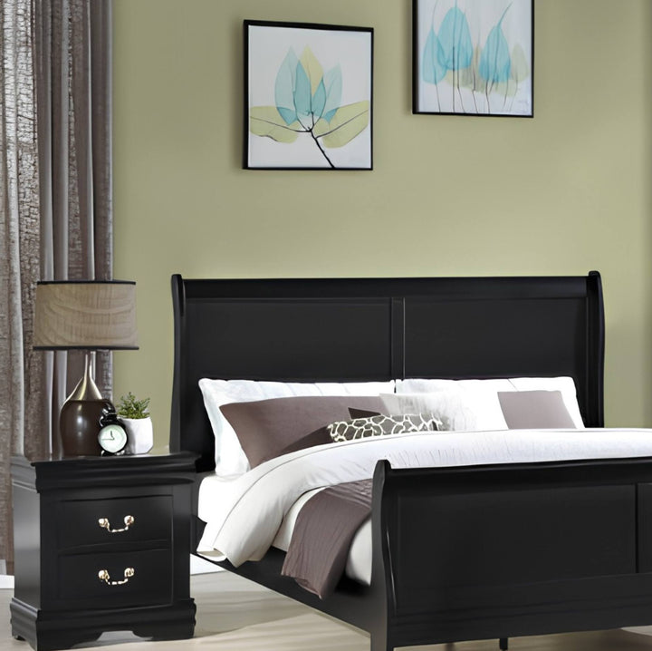 A black wooden sleigh bed with white bedding and brown accent pillows, styled in a bedroom with a matching black nightstand, lamp, olive green wall, and framed botanical art.