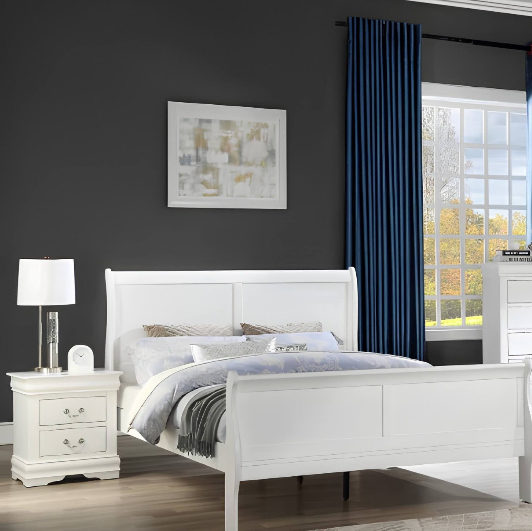 A white wooden bed frame with a tall panel headboard and footboard, styled with white and gray bedding in a modern bedroom setting with a dark gray wall, blue curtains, and a matching white nightstand.