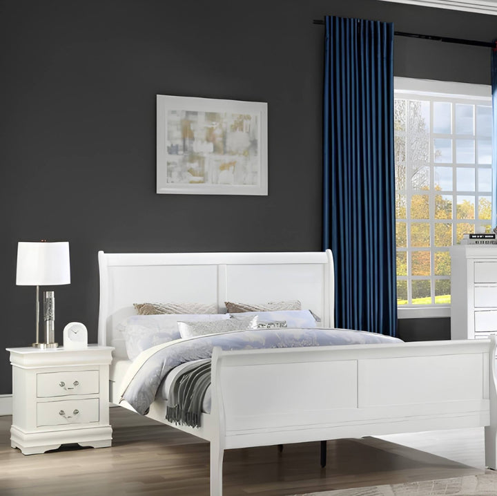 A white wooden bed frame with a tall panel headboard and footboard, styled with white and gray bedding in a modern bedroom setting with a dark gray wall, blue curtains, and a matching white nightstand.