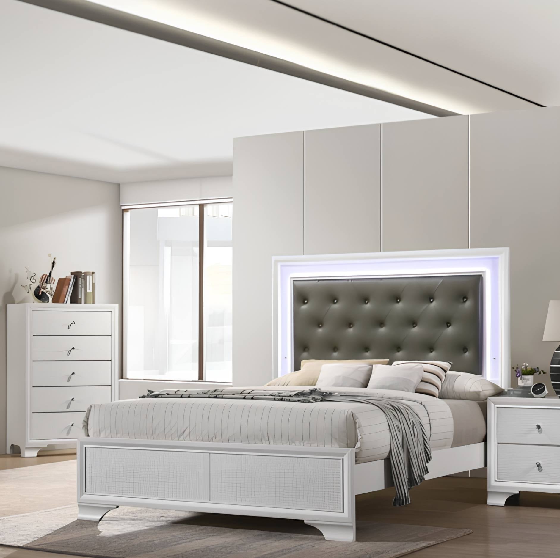 A modern bedroom featuring a white bed frame with a tufted gray headboard and integrated LED backlighting, styled with neutral bedding. The room includes a matching white dresser, nightstand, and a gray wall cabinet.
