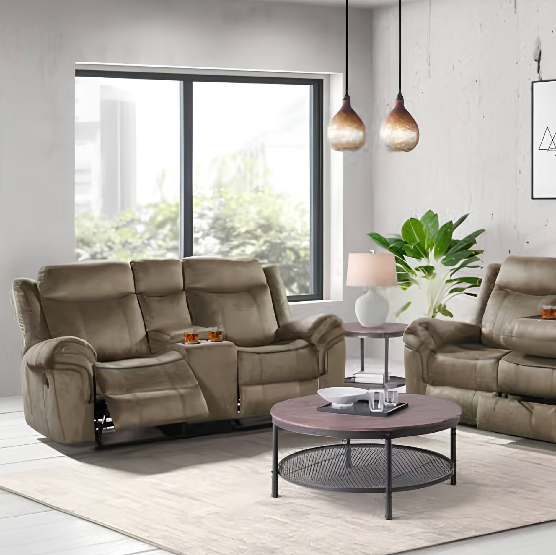 A modern living room setup featuring a taupe-brown reclining loveseat with an extended footrest, a matching armchair, a round coffee table, and a side table with a lamp and plant, set against a light gray wall with a large window.