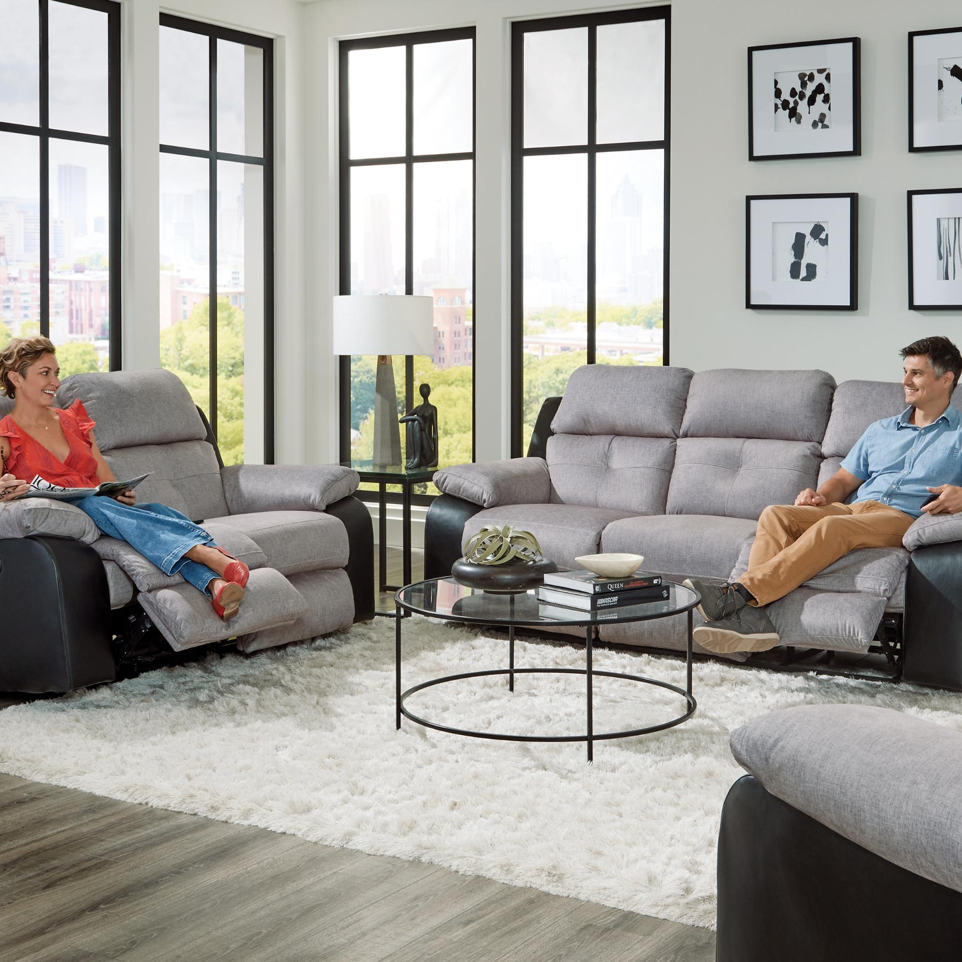 Living room with gray sofa set and people sitting on it, large windows in the background
