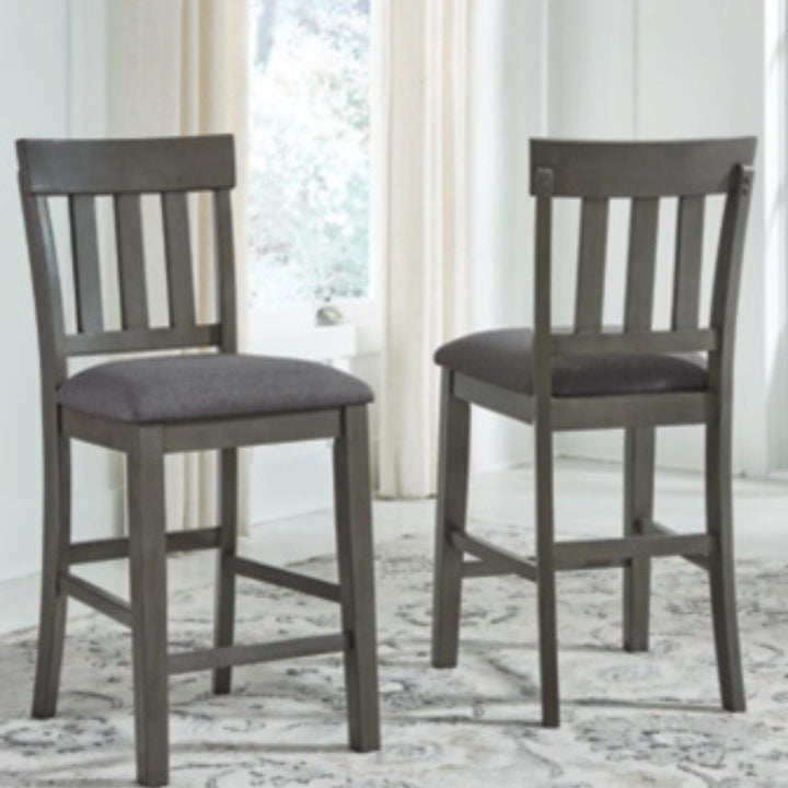 Two gray bar stools with cushioned seats on a patterned rug.