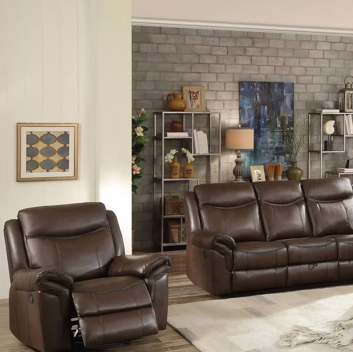 A brown leather recliner chair and matching three-seat sofa arranged in a styled living room with a brick accent wall, shelving, artwork, and a light rug.