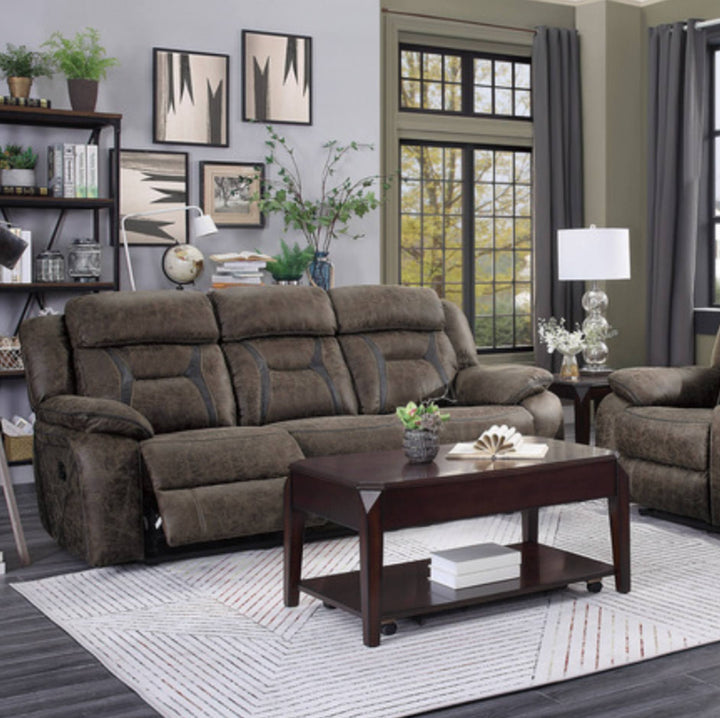 A brown upholstered reclining loveseat sofa in a staged living room setting, shown with a matching armchair, dark wood coffee table, rug, shelving, and wall art.