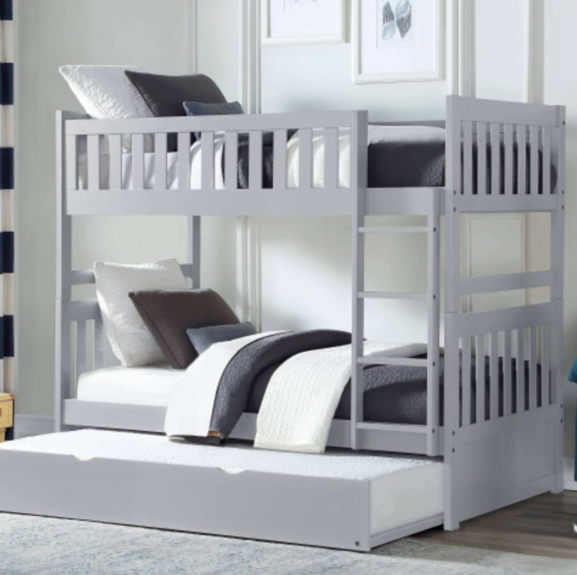 A light gray wooden bunk bed with a matching pull-out trundle bed, styled with white and dark gray bedding in a bright bedroom setting.