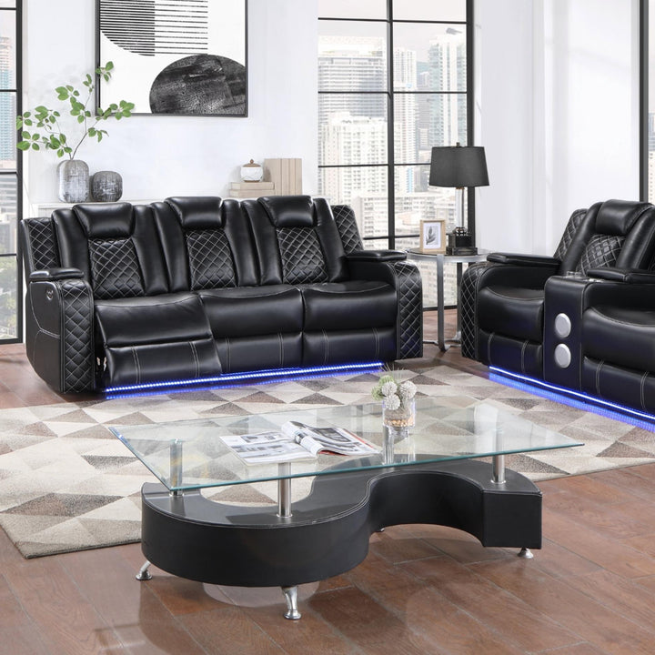 Black leather sofa set with glass coffee table in a modern living room.