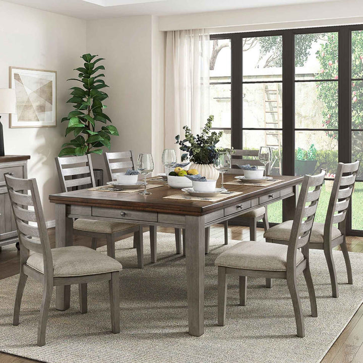 Dining room with a wooden table and gray chairs, decorated with plants and glasses.