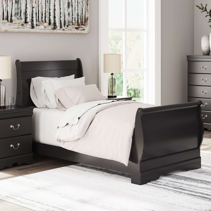 Black sleigh bed in a bedroom setting with white bedding and nightstands.