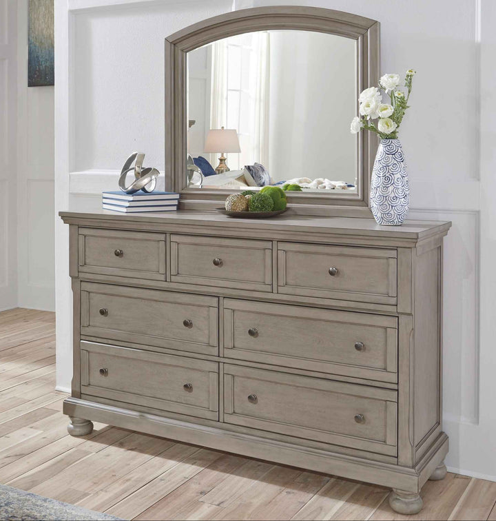 Wooden dresser with mirror and decorative items in a room.