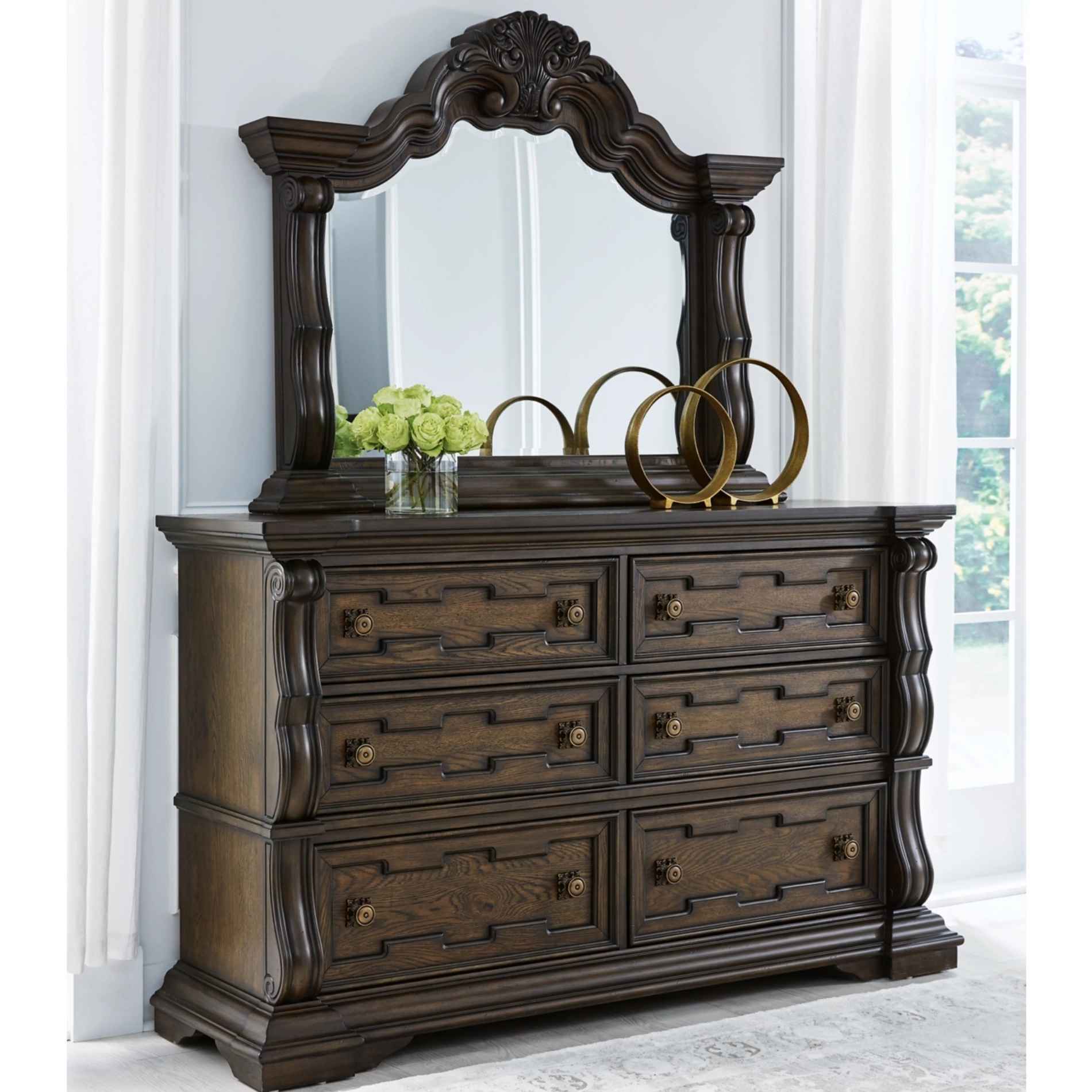Dark wood dresser with mirror in a room with white walls and a window.