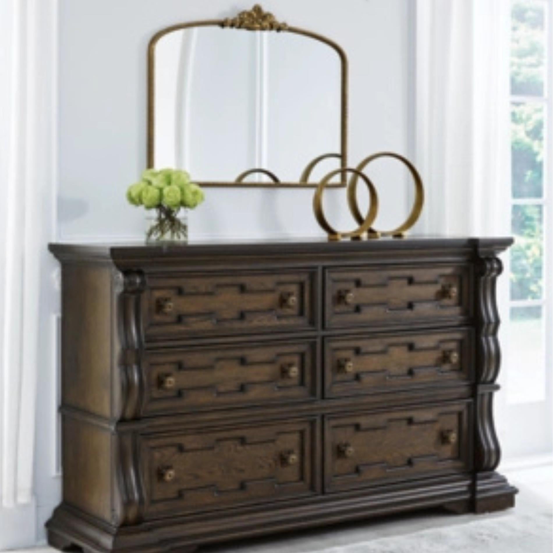 Dark wood dresser with decorative items including a mirror, flowers, and rings on a light background